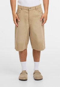 Lichte katoenen shorts met een relaxte pasvorm, zijzakken en een knoopsluiting. Draag ze met witte crew-sokken en beige instappers.