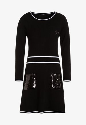 Robe en maille noire à manches longues, bordure blanche au niveau du col et de l'ourlet, avec deux poches ornées de sequins. Coupe évasée et texture douce.
