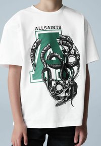 Valge puuvillane T-särk, millel on musta ja rohelist värvi seotud madude graafiline kujutis ning rasvases kirjas tekst "ALLSAINTS".