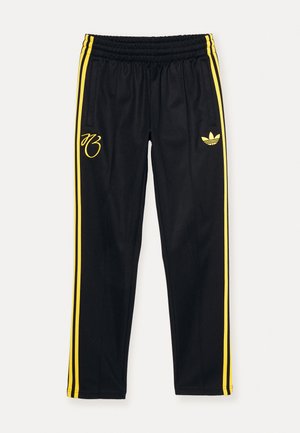 Pantalones deportivos negros con franjas laterales amarillas, cintura elástica y logo bordado en el muslo izquierdo. Fabricados con un material ligero y suave.