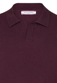 Bourgognefarvet polo i tekstureret stof med klassisk krave og et lille, hvidt mærke med logo ved halsudskæringen.