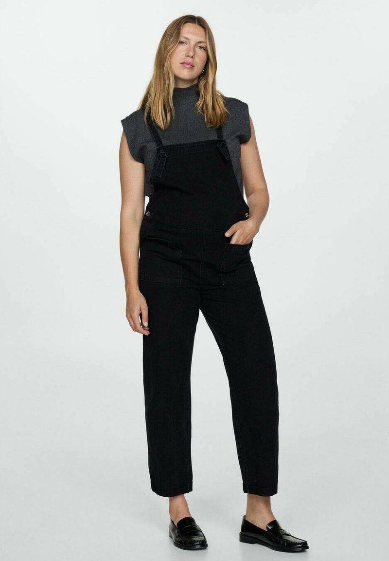 Zwarte denim salopettes met verstelbare banden, zijzakken en taps toelopende pijpen, gecombineerd met een grijze T-shirt met korte mouwen, gedragen met zwarte instappers.