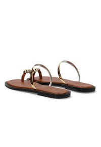 Sandalias planas marrones con suelas negras, que cuentan con tiras finas doradas y transparentes sobre los dedos y alrededor del pie.