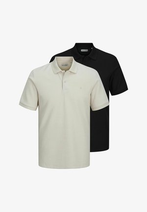 Chemise polo noire avec une finition texturée, associée à un pantalon noir ample et à des chaussures noires imposantes ; design simple et minimaliste.