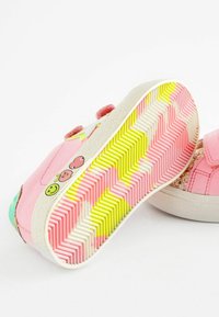 Baskets roses avec un matériau texturé, ornées de graphiques de smileys et de fruits, et une semelle vibrante à motif zigzag en rose, blanc et jaune.