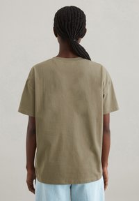 Olivgrünes Baumwoll-T-Shirt mit kurzen Ärmeln und lässiger Passform, mit Rundhalsausschnitt und glatter Textur. Keine sichtbaren Muster oder Akzente.