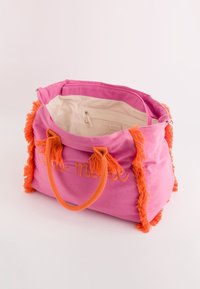 Leinen-Tote-Bag in leuchtendem Pink mit orangefarbenen Fransen und Akzenten. Verfügt über einen Reißverschluss und ein beiges Innenfutter mit einer Tasche.