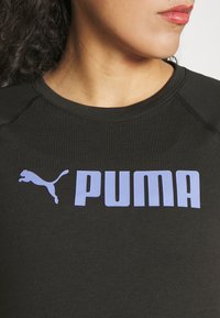 Černé sportovní tričko s krátkými rukávy má na přední straně velké fialové logo "PUMA" a siluetu skákající pumy.