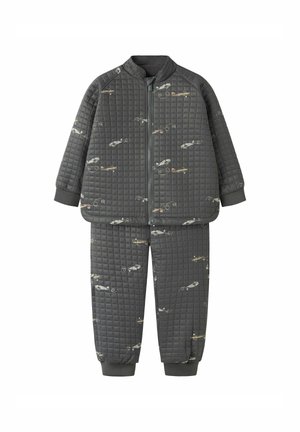 Gepolsterter grauer Trainingsanzug mit einer Reißverschlussjacke und elastischen Bündchen, der ein sich wiederholendes Flugzeugmuster und eine durchgehend glatte Textur aufweist.