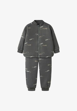 Survêtement matelassé gris avec une veste zippée et des poignets élastiques, arborant un motif d'avion répété et une texture lisse sur l'ensemble.