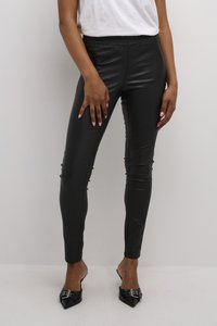 Schwarze Leggings aus Kunstleder mit elastischem Bund, schlankem Design und seitlichen Nähten, kombiniert mit spitzen schwarzen Absätzen.