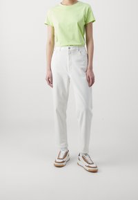 Vaaleanvihreä lyhythihainen t-paita, valkoiset korkeat farkut ja valkoiset tennarit ruskeilla yksityiskohdilla ja teksturoidulla pohjalla.