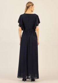 Navyblaues Maxikleid mit Schmetterlingsärmeln, tailliertem Bund und tiefem Rückenausschnitt. Weiche Textur mit fließender Silhouette.