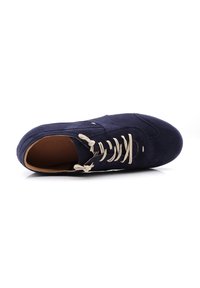 Navy suede sneaker with a round toe, beige laces, stitch detailing, and a light interior. Sole appears flat and smooth.