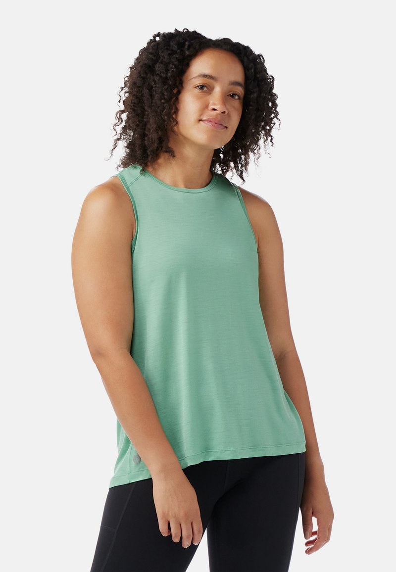 Top deportivo sin mangas verde, hecho de un material suave con un corte holgado, escote redondeado y detalles de costura mínimos. Combinado con leggings negros.