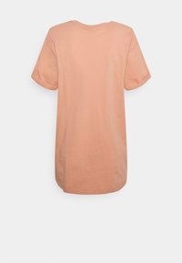 Lyhyt persikanvärinen T-paita, valmistettu puuvillasta, lyhyillä hihoilla, pyöreällä kauluksella ja hieman pidemmällä takahännällä. Sileä pinta, ilman kuvioita.