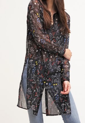 Harmaa läpikuultava paita, jossa on punaisia, sinisiä ja keltaisia kukkakuvioita. Varustettu kauluksella, pitkillä hihoilla ja sivurei'illä. Kevyt kangas.