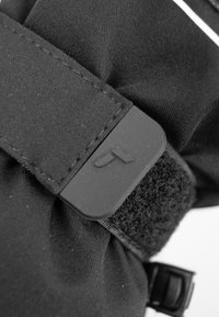 Cinturino in tessuto nero con una fibbia rettangolare in plastica che presenta un logo e chiusura in Velcro, mostrando dettagli di texture e cuciture.