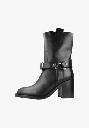 Botte en cuir noir mi-mollet avec talon bloc, sangle décorative et détail de boucle argentée, vue de côté extérieur.