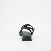 Černá kožená sandála s nízkým blokovým podpatkem, zdobená pletenými popruhy a nastavitelným sponou na kotníku. Hladký povrch s minimalistickým designem.