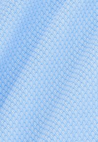 Tessuto azzurro chiaro con un motivo intrecciato strutturato. Il design presenta forme imbrigliate con una lieve lucentezza.