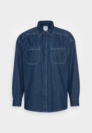 Donkerblauw denim shirt met knopenlijst aan de voorkant, twee borstzakken en lange mouwen met een relaxed fit en zichtbare stiksels.