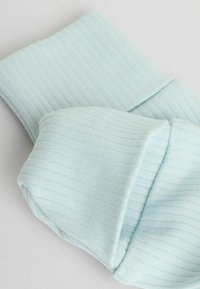 Lyseblåt ribbet stof med en blød tekstur, der har en foldet manchet og ensartede horisontale linjer.