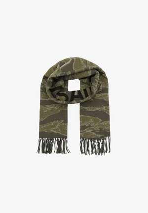 Gebreide sjaal in olijfgroen met camouflagepatroon en zwarte letters. Heeft franje aan de uiteinden en een zachte textuur. Rechthoekige vorm.