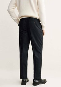 Pantaloni neri a righe sottili realizzati in tessuto intrecciato, con vestibilità slim, tasca posteriore e completati da scarpe in pelle nera.