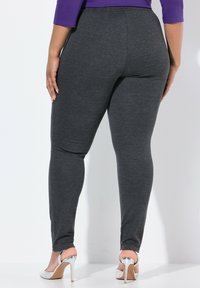 Tummanharmaat legginsit, jotka on valmistettu venyvästä materiaalista, joissa on slim fit -leikkaus ja sileä pinta, yhdistettynä metallisiin korkokenkiin.