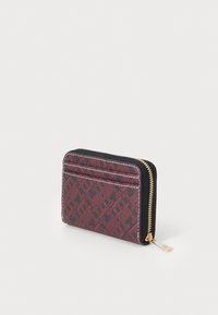Zippered card wallet in red and black patterned material, featuring multiple card slots and gold-tone zipper hardware. Textured surface.