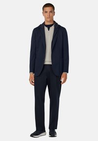 Jūras zils bleizeris ar kapuci, aizpogājams priekšpuse, divas kabatas; krēmkrāsas ar rāvējslēdzēju tops; piegriezuma jūras zila bikses; melni sporta apavi. Gluda auduma tekstūra.