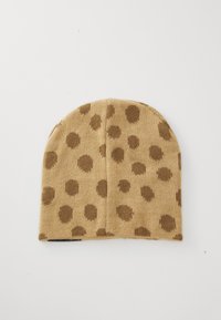Bruine polkadot-bini van een tan gebreide stof, met een afgeronde vorm aan de bovenkant, een zachte textuur en een omgevouwen band aan de onderkant.