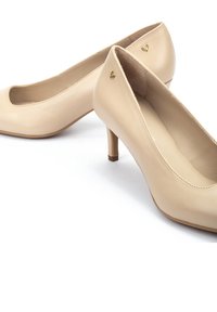 Zapatos de tacón alto de cuero beige con punta redondeada, pequeño corte en la parte delantera y un logo dorado en el lateral. Textura suave.