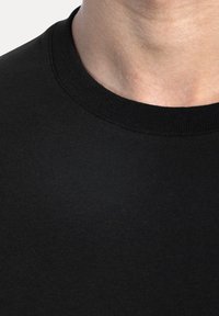 Maglietta nera con scollatura a girocollo realizzata in un tessuto liscio e texturizzato. Vista ravvicinata che mostra la scollatura ampia e la finitura morbida.