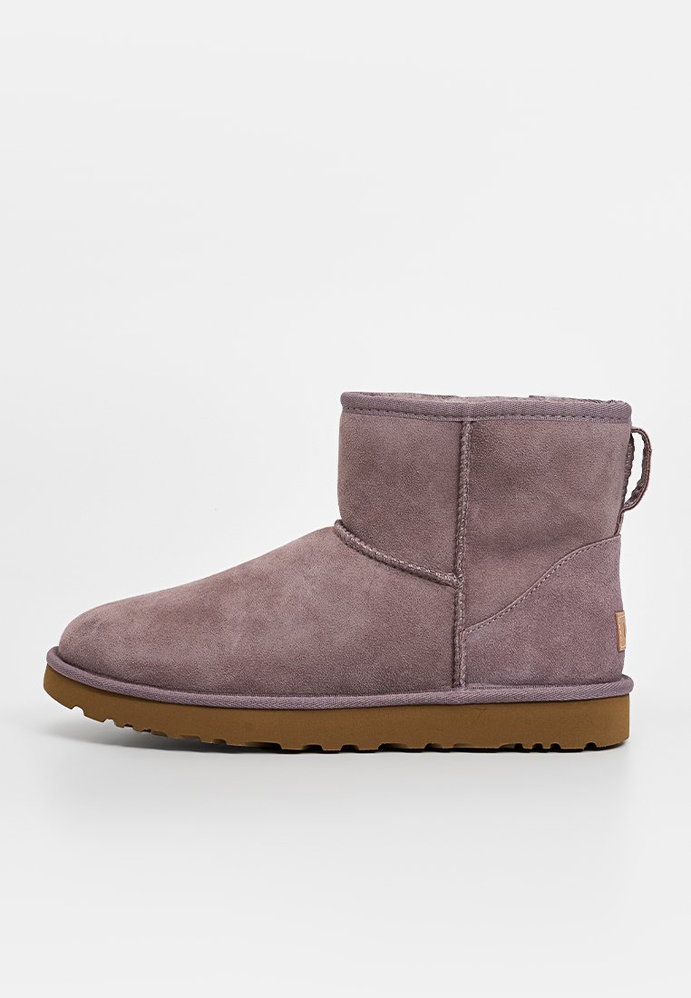 Lila Wildleder-Ankle-Boot mit einer runden Zehenpartie, minimalen Nähten, einem niedrigen Absatz und einer strukturierten Gummisohle für besseren Halt. Mit Zuglasche an der Rückseite.