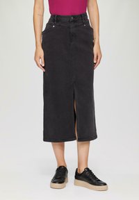 Musta denim-midi-hame, jossa on etureikä, korkea vyötärö, kaksi sivutaskua ja nappisuljenta. Yhdistetty mustiin lenkkareihin ja violettiin puseroon.