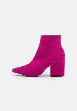 Fuchsia suède enkellaars met een puntige neus, brede hak en een gladde textuur. Voorzien van een hoge schacht en een minimalistisch ontwerp.