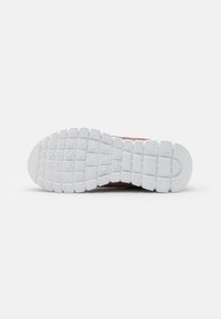 Baskets de sport rouges avec une semelle en caoutchouc blanc. La semelle présente un motif de grille texturé pour l'adhérence. La tige ne montre aucune marque visible.