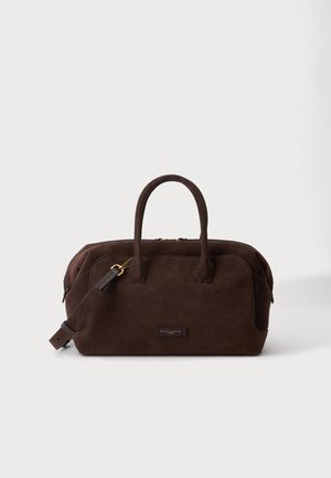 Sac à main en daim marron foncé avec double poignée, une bandoulière amovible et une petite plaque rectangulaire avec logo sur le devant.