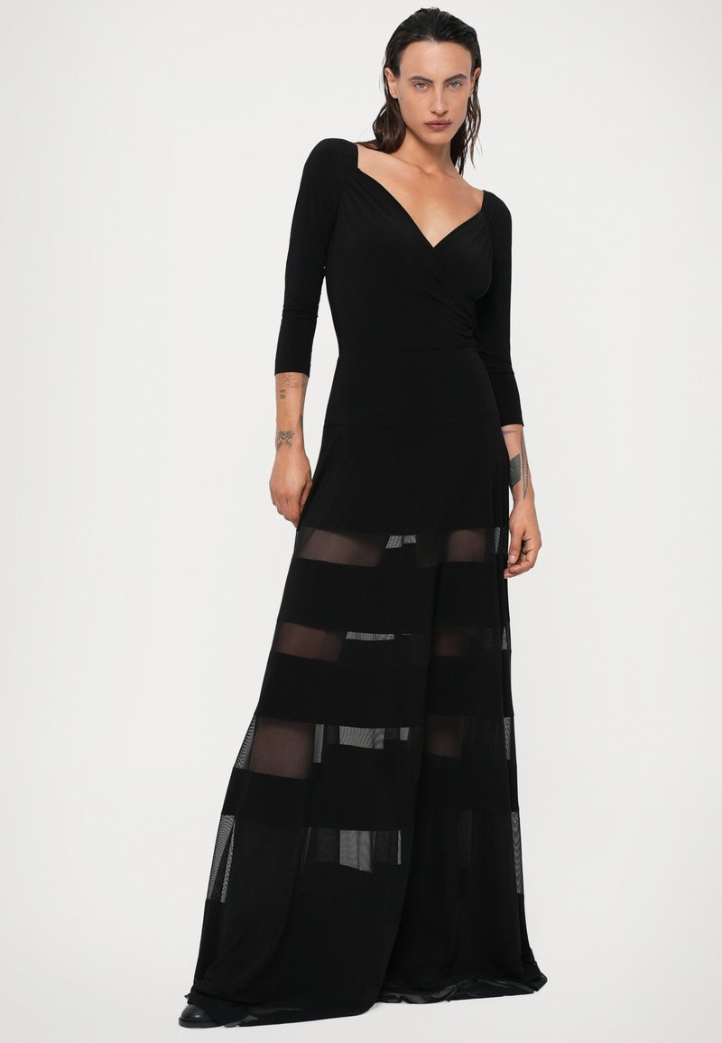 Black long dress featuring a wrap design, long sleeves, and sheer striped panels at the skirt. Made of lightweight, flowing fabric.