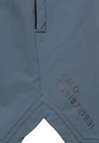 Blauwe stof met een ritszak en gestikte details, met gedrukte cijfers en het woord "HALO" in donkergrijs.