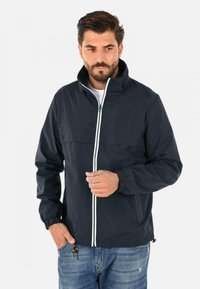 Giacca a vento blu navy con collo alto, cerniera bianca e polsini elastici. Tessuto morbido, design leggero e tasca frontale.