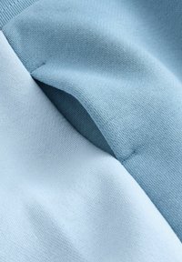 Tissu bleu clair présentant deux couches texturées avec finitions côtelées et lisses, doté d'une surface mate et de bords sans coutures.