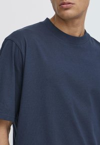 Tricou bleumarin cu guler rotund, fabricat din bumbac, cu mâneci scurte și o textură netedă, fără modele sau accente vizibile.