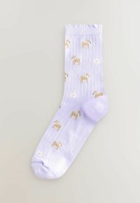 Chaussette en coton violet clair avec une texture côtelée et un motif décoratif de petits chiens marron et de soleils. Poignet froncé et embout arrondi.