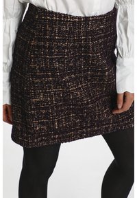 Stickad kjol i mörklila och beige texturerad tyg. Har en figurnära passform med rak fåll och sidofickor.