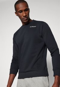 Navy sweatshirt gemaakt van zachte stof met een ronde hals en lange mouwen. Voorzien van een witte Kappa logo op de borst. Aangevuld met ribgebreide manchetten.