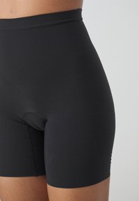 Black high-waisted shorts made of smooth, stretchy fabric. Features a fitted design and a mid-thigh length. No visible hardware or patterns.