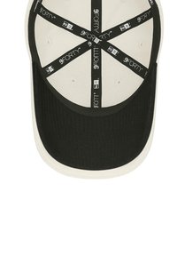 Black and cream baseball cap with a textured black bill, white top, and a patterned inner band featuring "9FORTY" text and logo.